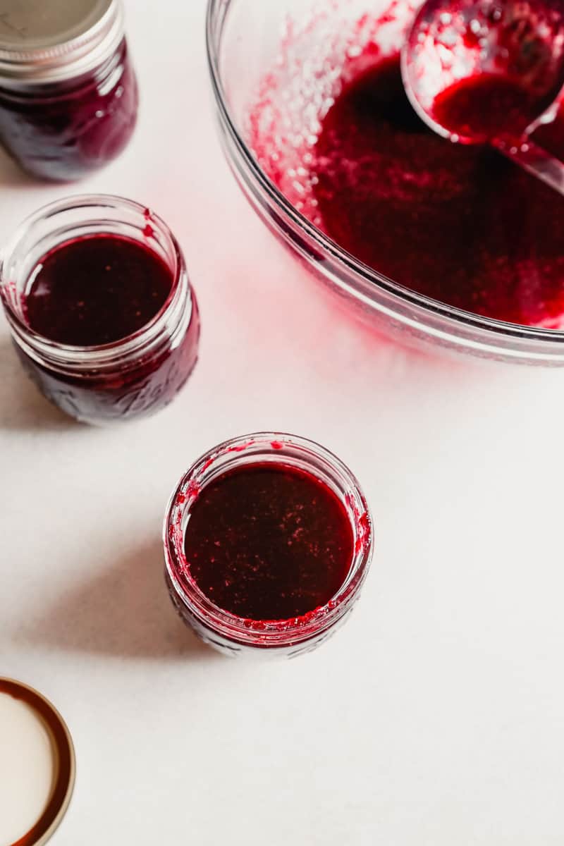 Homemade cherry jam in a glass jar on a table with other jam jars