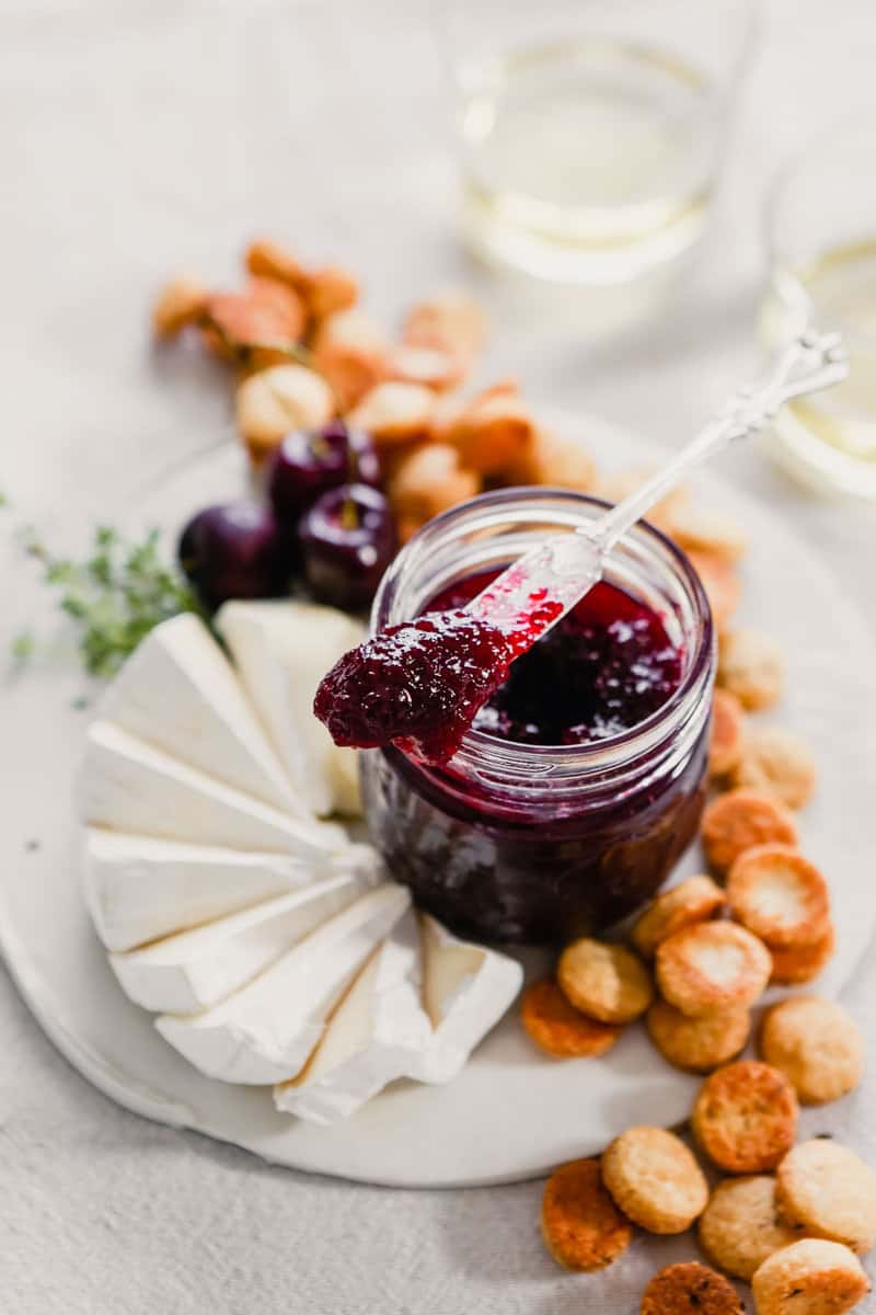 photograph of homemade cherry jam on a plate with crackers and cheese