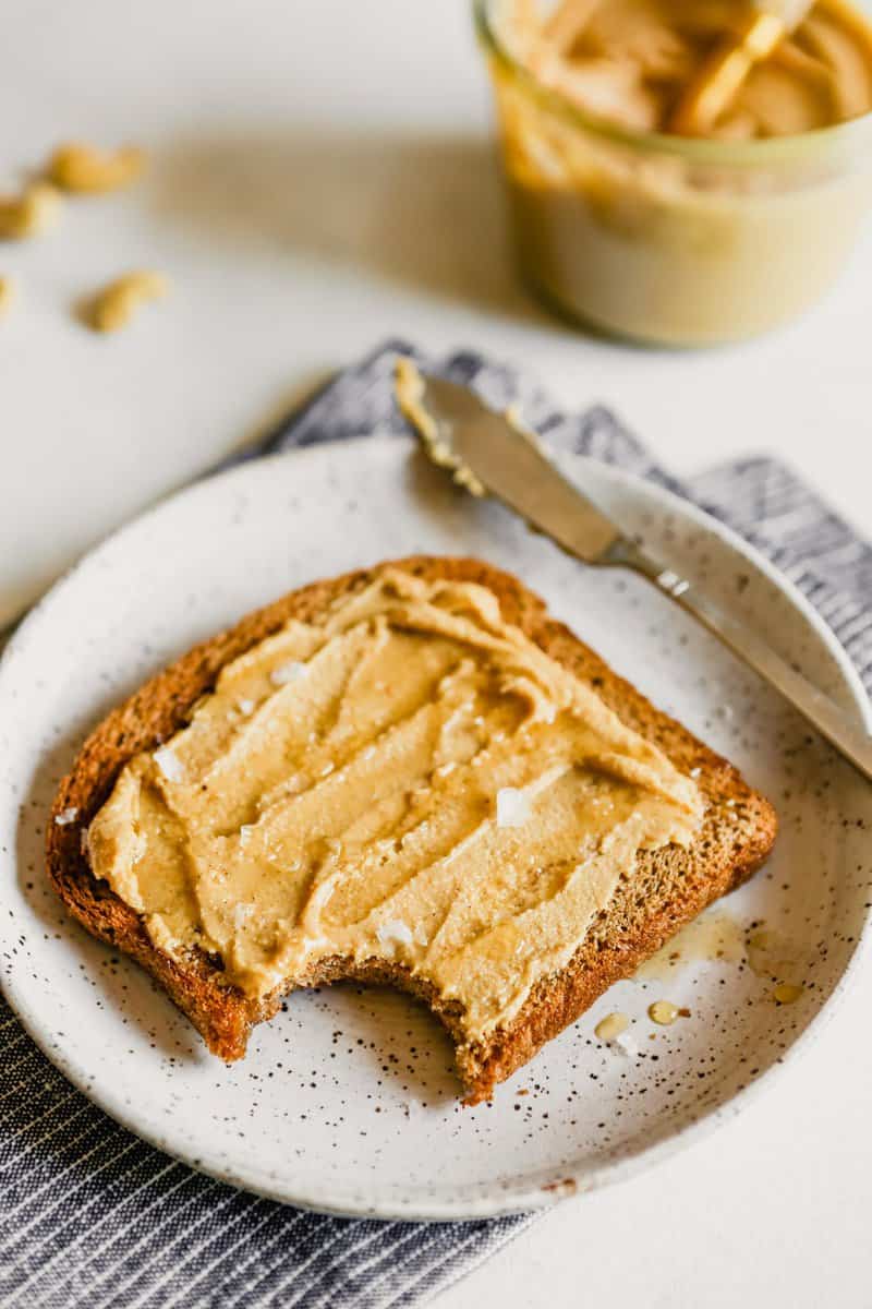 Photo of cashew butter spread onto a piece of toast with honey and sea salt