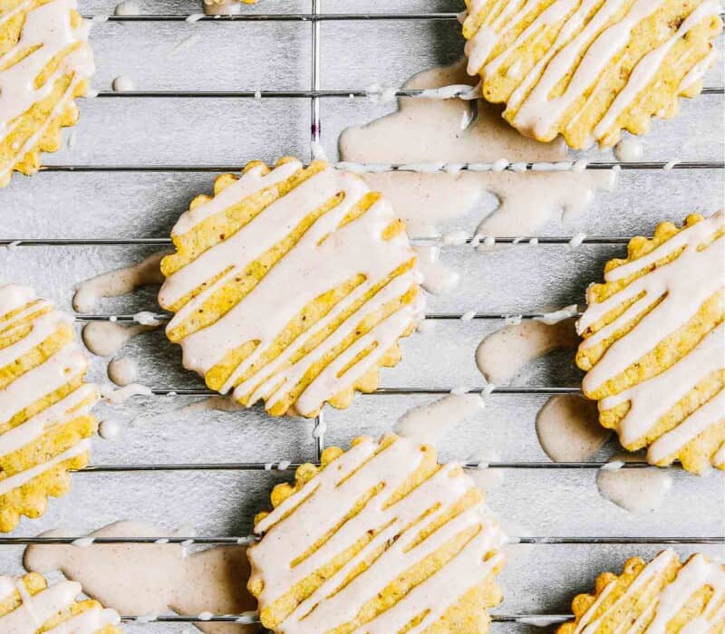 Iced pumpkin cookies set on a wire rack with glaze all over coutertop