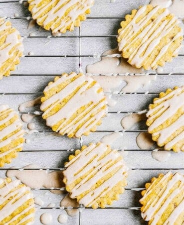 Iced pumpkin cookies set on a wire rack on a concrete table.