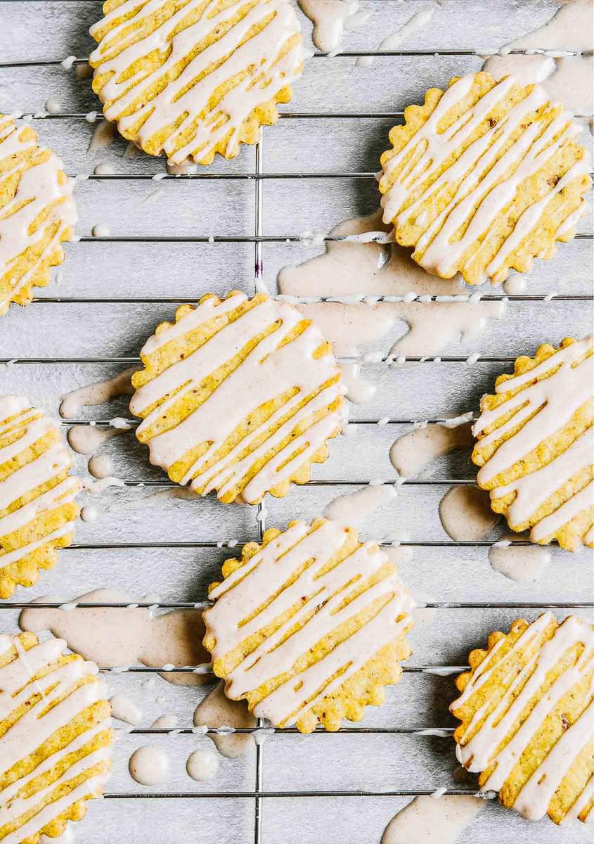 Iced pumpkin cookies set on a wire rack on a concrete table.