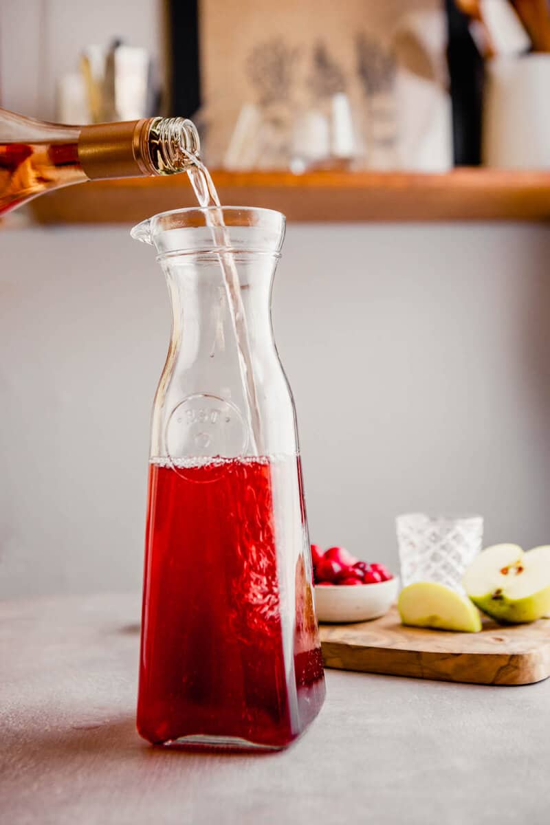 Photograph of rose wine being poured into a pitcher to make fall sangria.