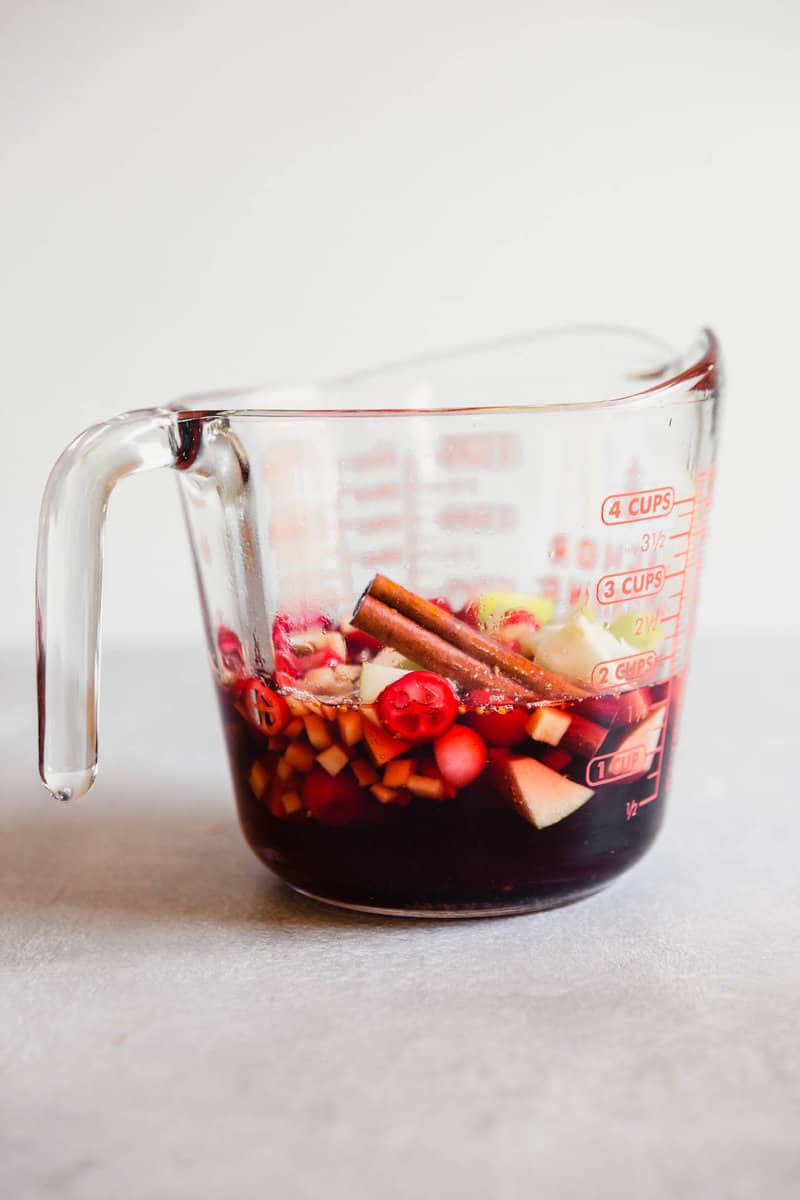Photograph of a flavored cranberry simple syrup in a glass measuring cup.
