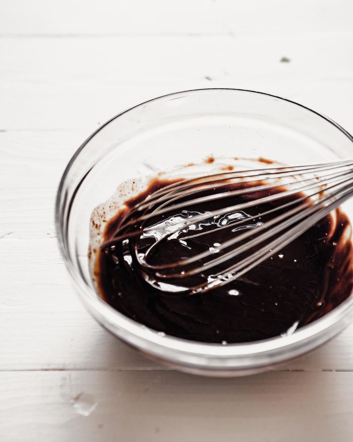 a smooth and shiny ganache in a glass bowl with a whisk