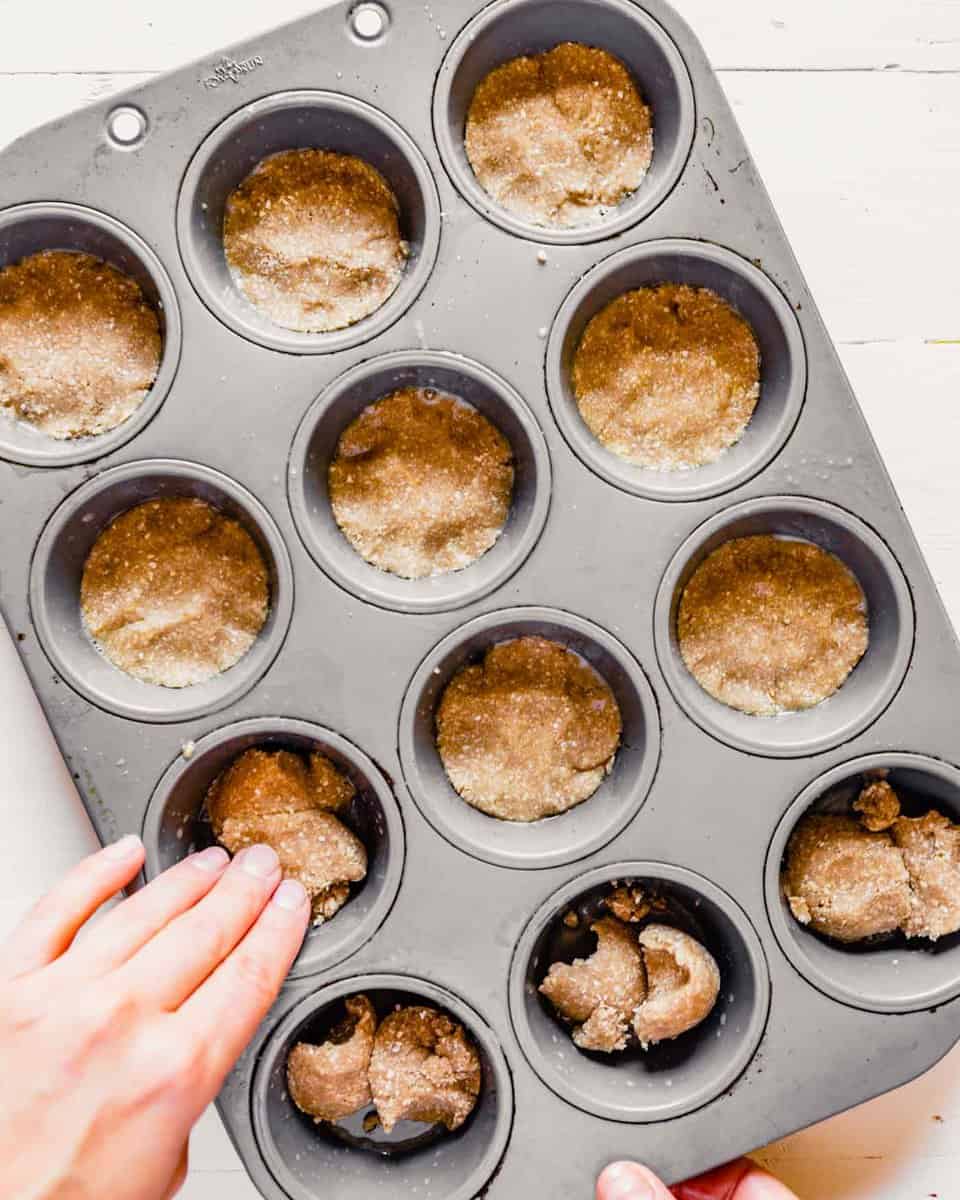 overhead image of dough being pressed into a muffin tin