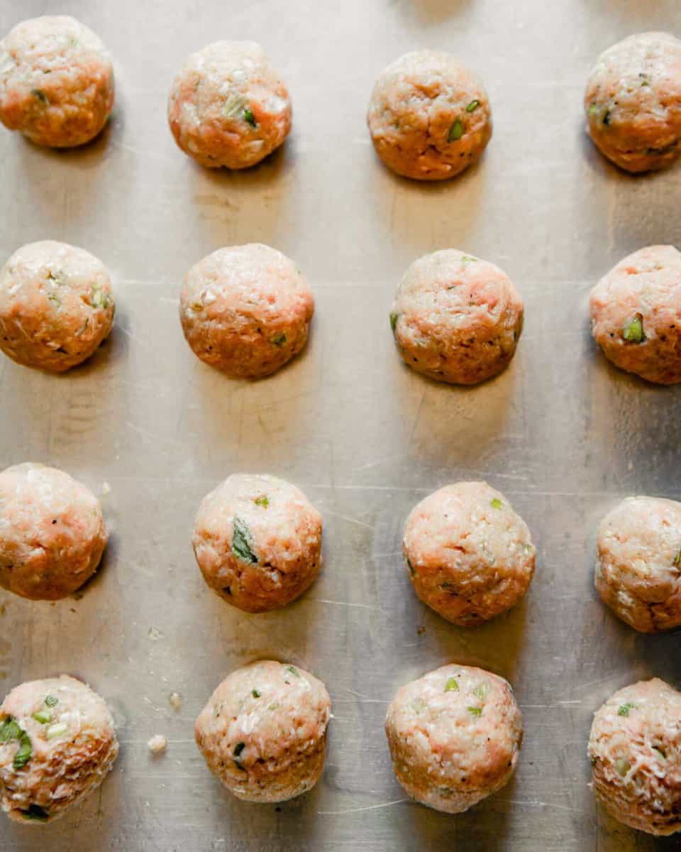 Overhead photo of raw turkey meatballs arranged on a baking sheet
