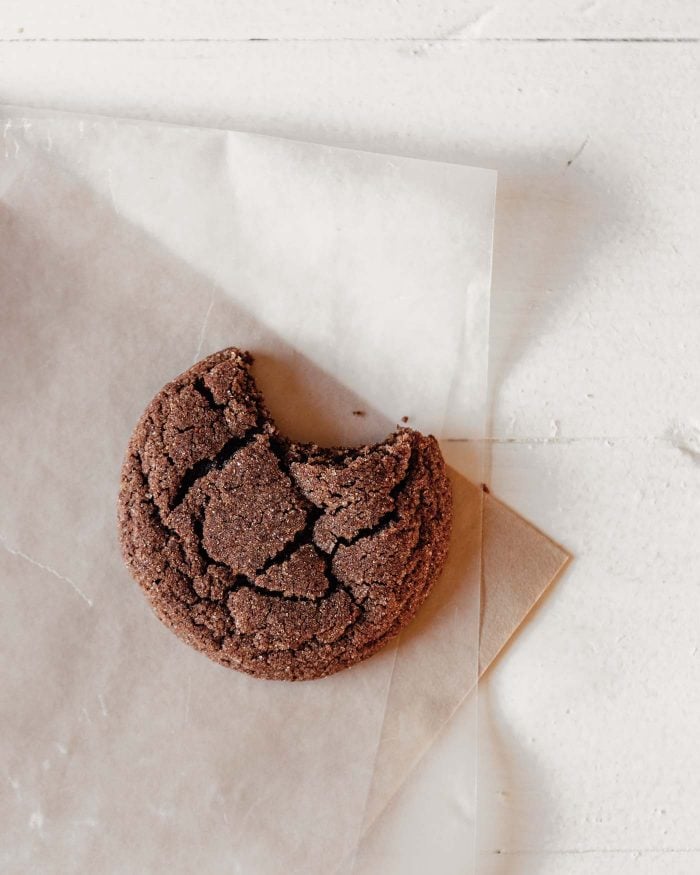 overhead photo of a single chocolate cookie set on parchment paper with a bite taken out of it