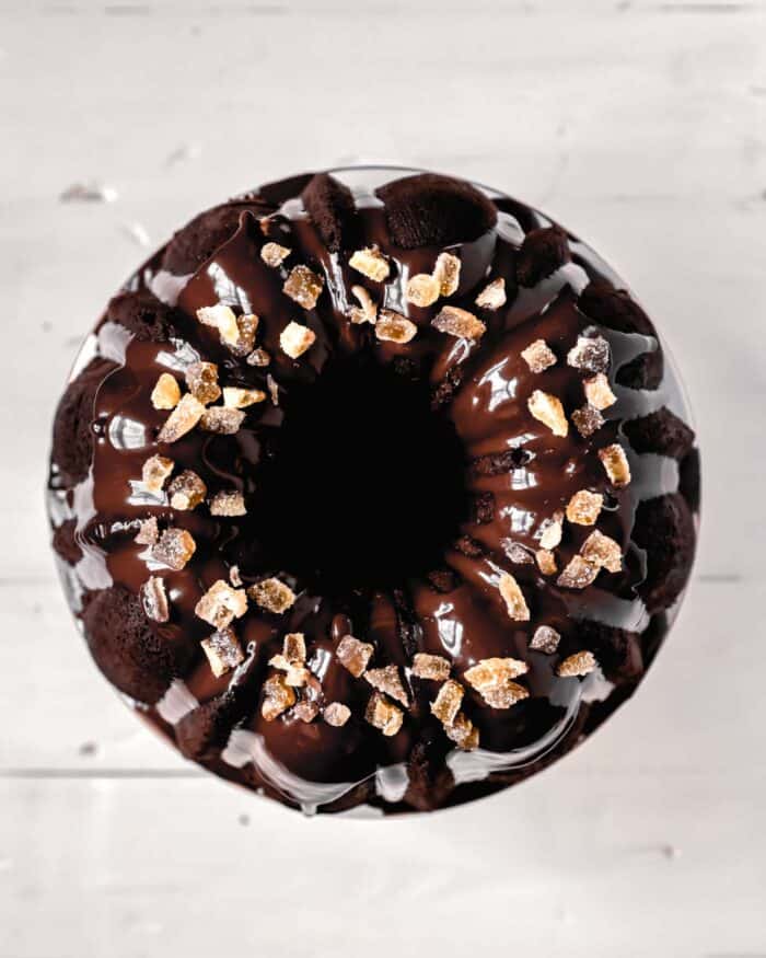 Overhead image of a chocolate bundt cake with a shiny chocolate glaze and candied ginger