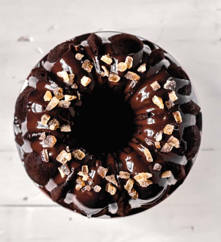 Overhead image of a chocolate bundt cake with a shiny chocolate glaze and candied ginger