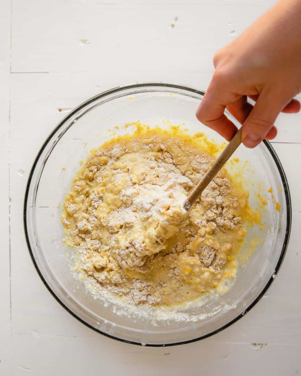 Overhead photo of batter being mixed together in a glass bowl set on a white table
