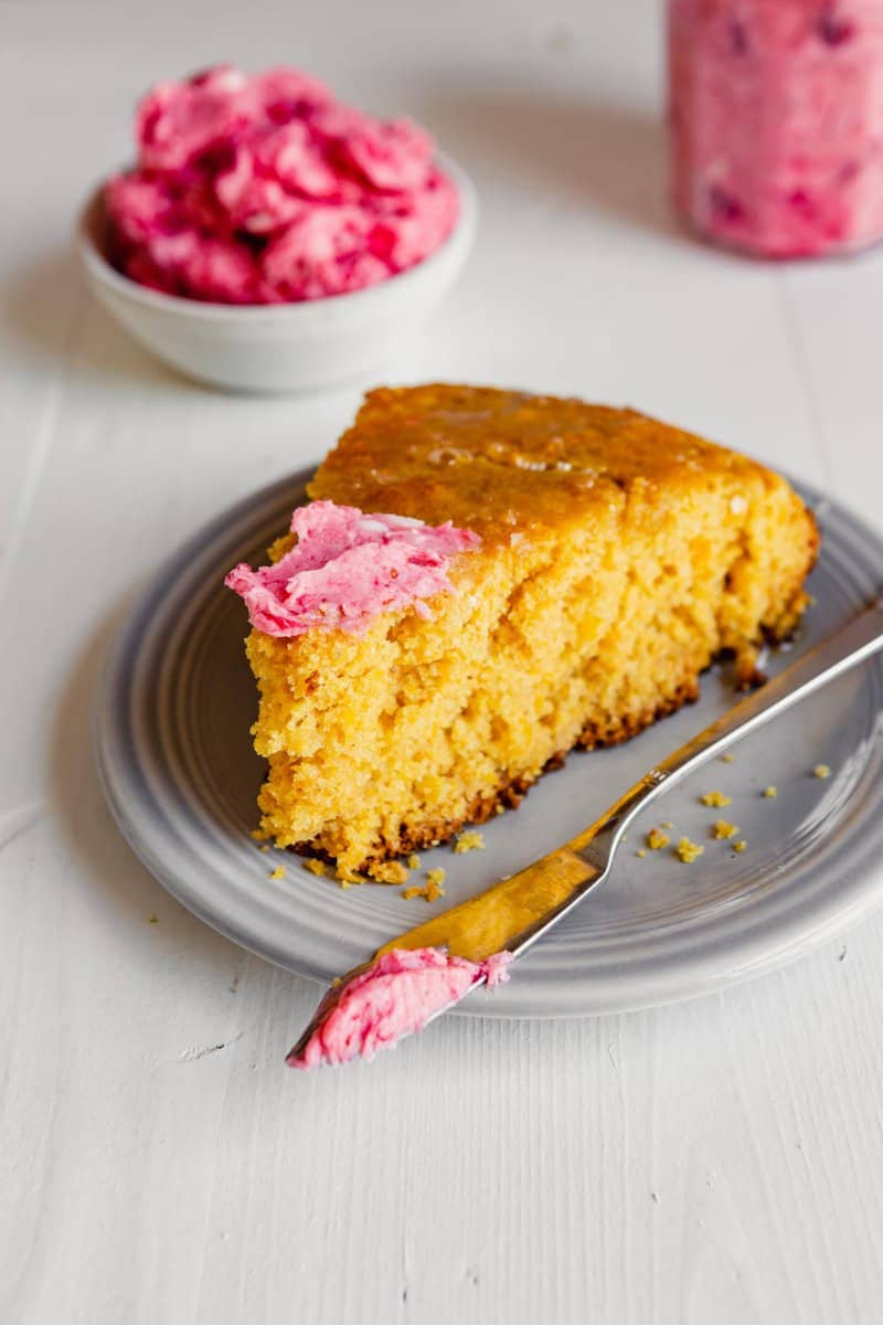 photo of a slice of cornbread with cranberry butter spread over top of it