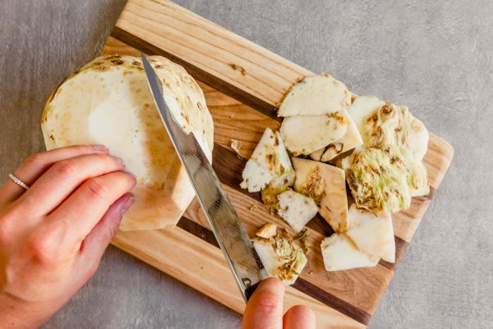 Overhead photo of celery root being peeled with a chef's knife