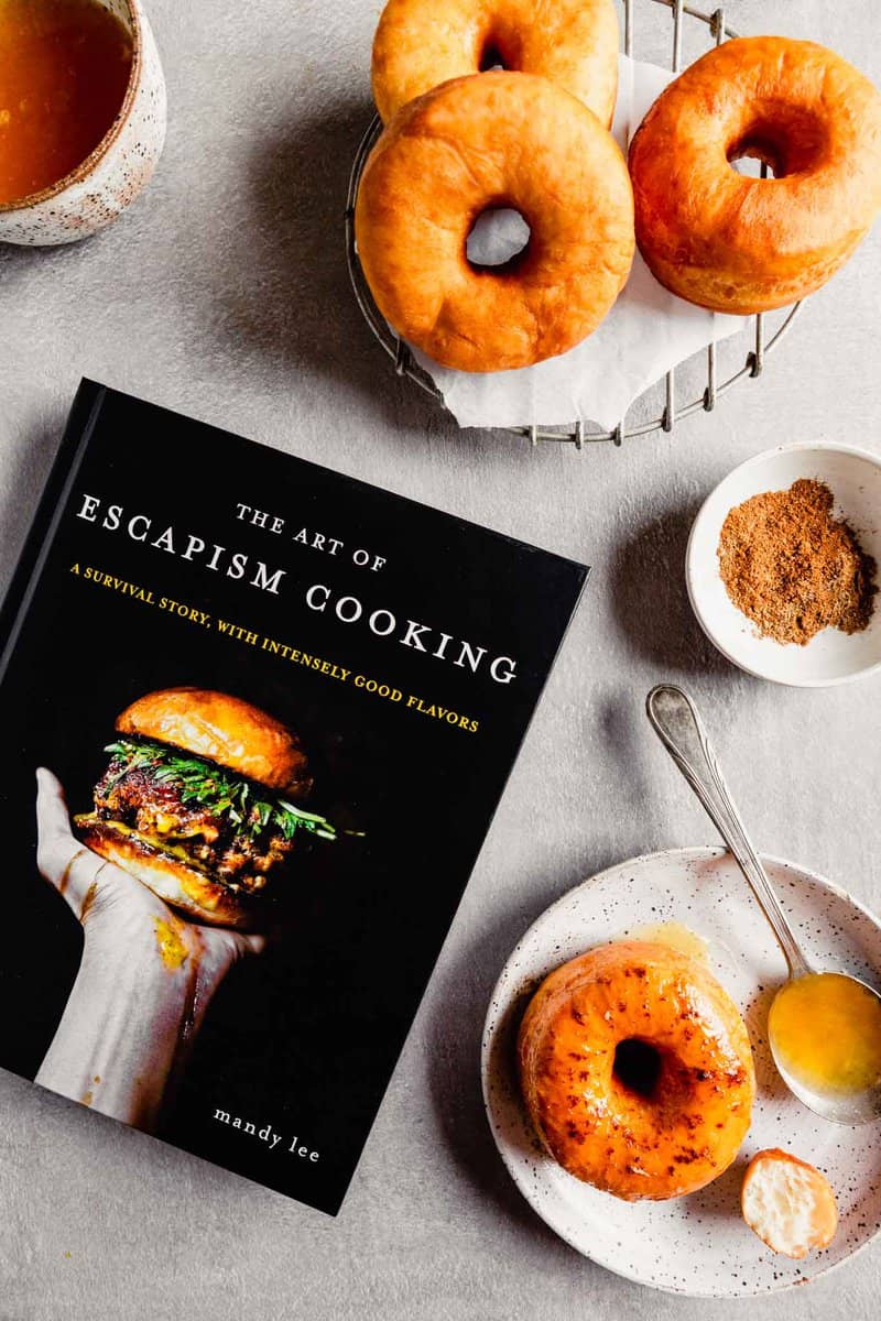 Overhead image of the Art of Escapism Cooking cookbook with donuts spread around it