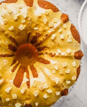 Photograph of orange and ginger bundt cake with turmeric glaze on glass cake stand