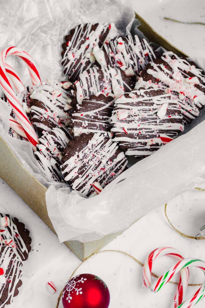 chocolate peppermint cookies arranged in a gift box with candy canes and ornaments set around it