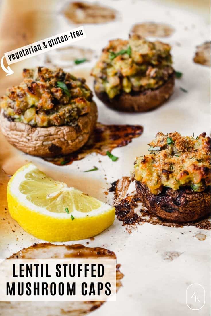 Stuffed cremini mushrooms on a baked piece of parchment paper with a lemon wedge in the center