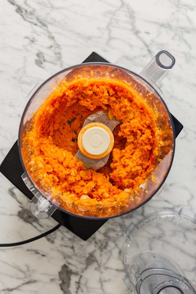 Overhead image of chopped chickpeas and sweet potato puree in a food processor