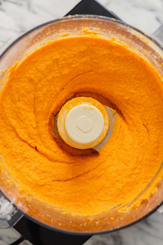 overhead image of super creamy orange hummus in a food processor