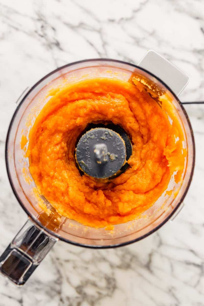 Pureed sweet potato mixture in a mini food processor set on a white marble table