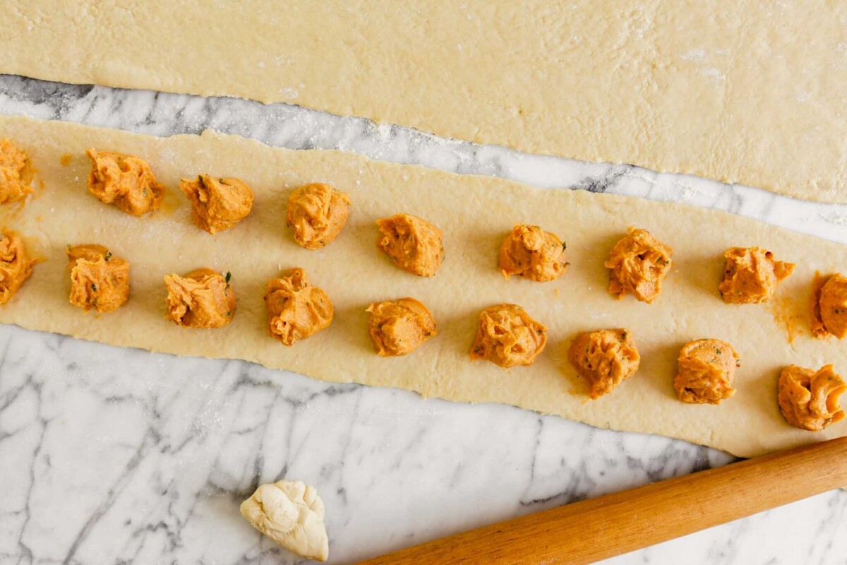 dollops of vegan ravioli filling arranged in two rows down a long rectangular piece of dough
