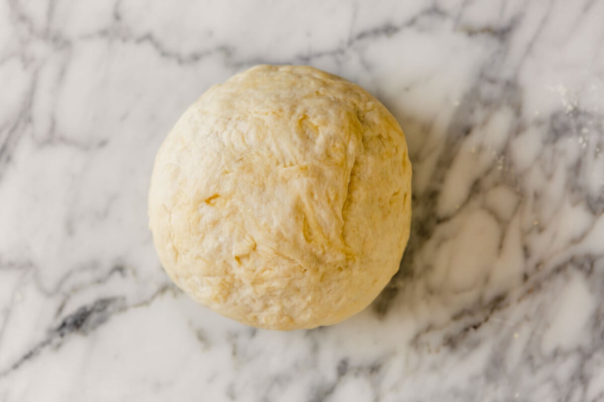 overhead image of a large dough ball on a marble table
