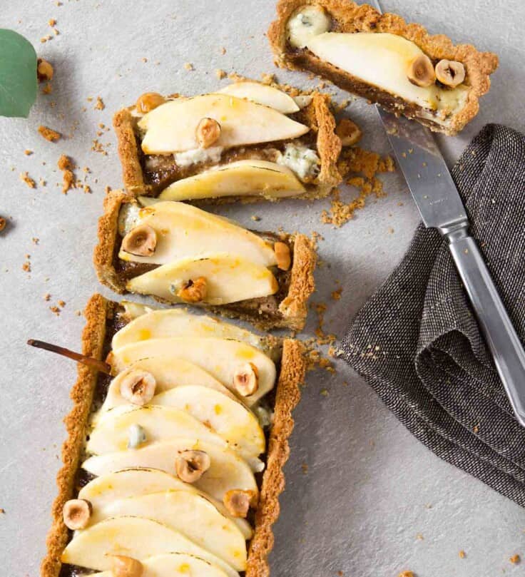 Overhead image of a tart sliced and laying on a gray table with a knife off to the side