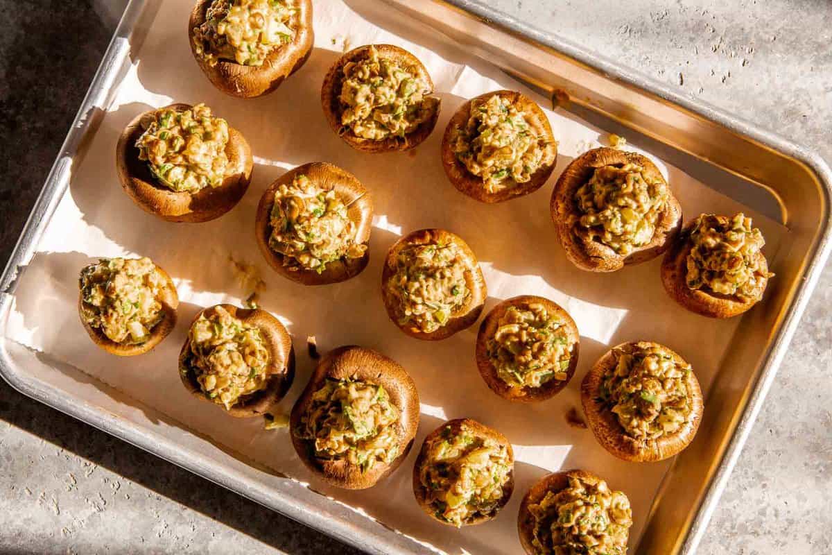 stuffed cremini mushrooms on a parchment-lined baking sheet