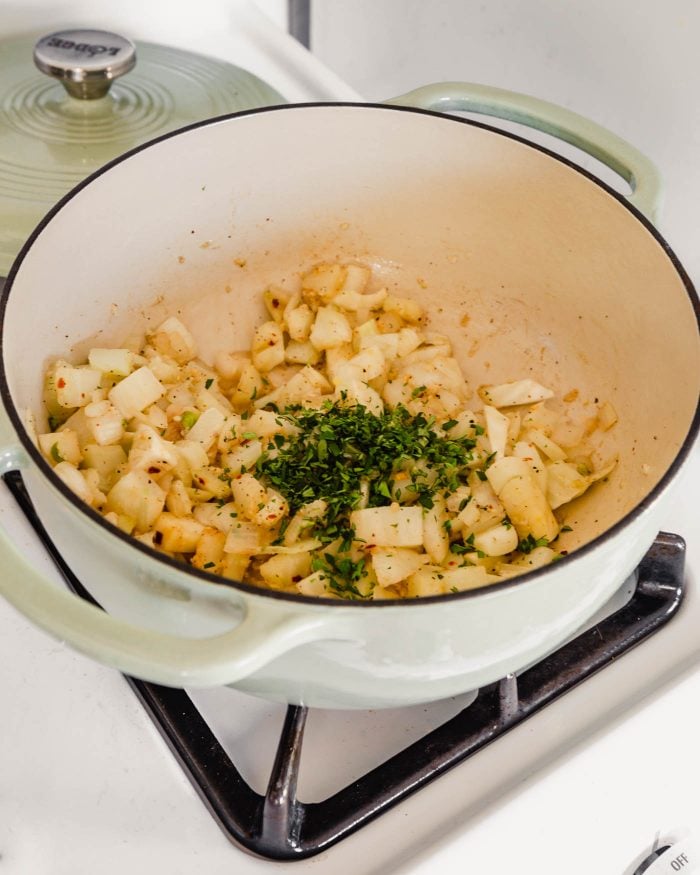 image of onions and herbs in a Dutch oven on the stove