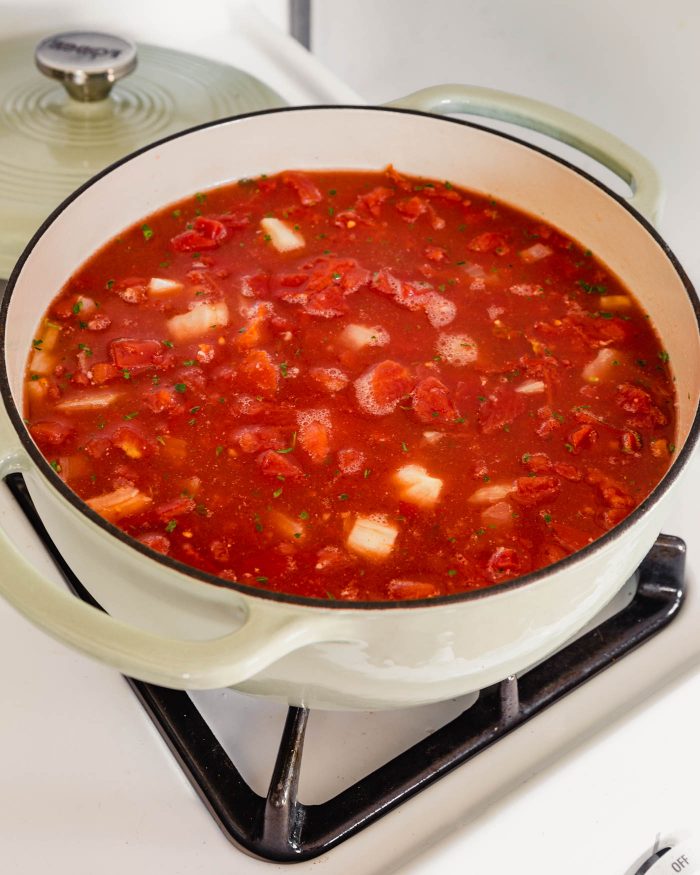 Image of canned tomatoes and broth in a large Dutch oven on the stove top