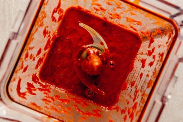 Overhead image of a bright red chile sauce in a blender