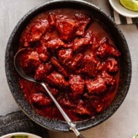 overhead image of deep red carne adovada in a dark gray bowl set on a gray table