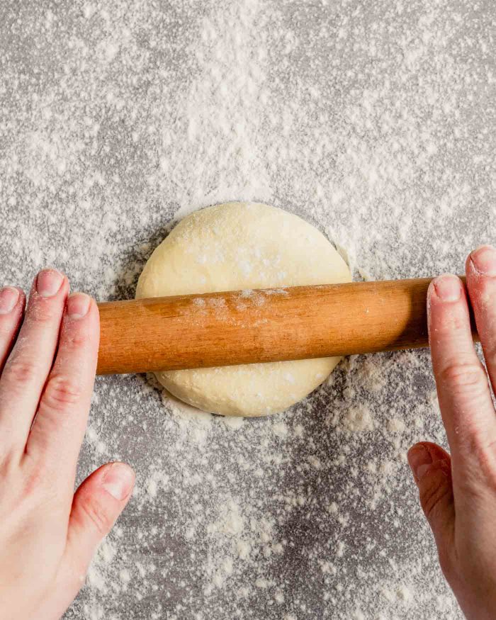 Overhead image of someone rolling out a piece of dough on a lightly floured surface