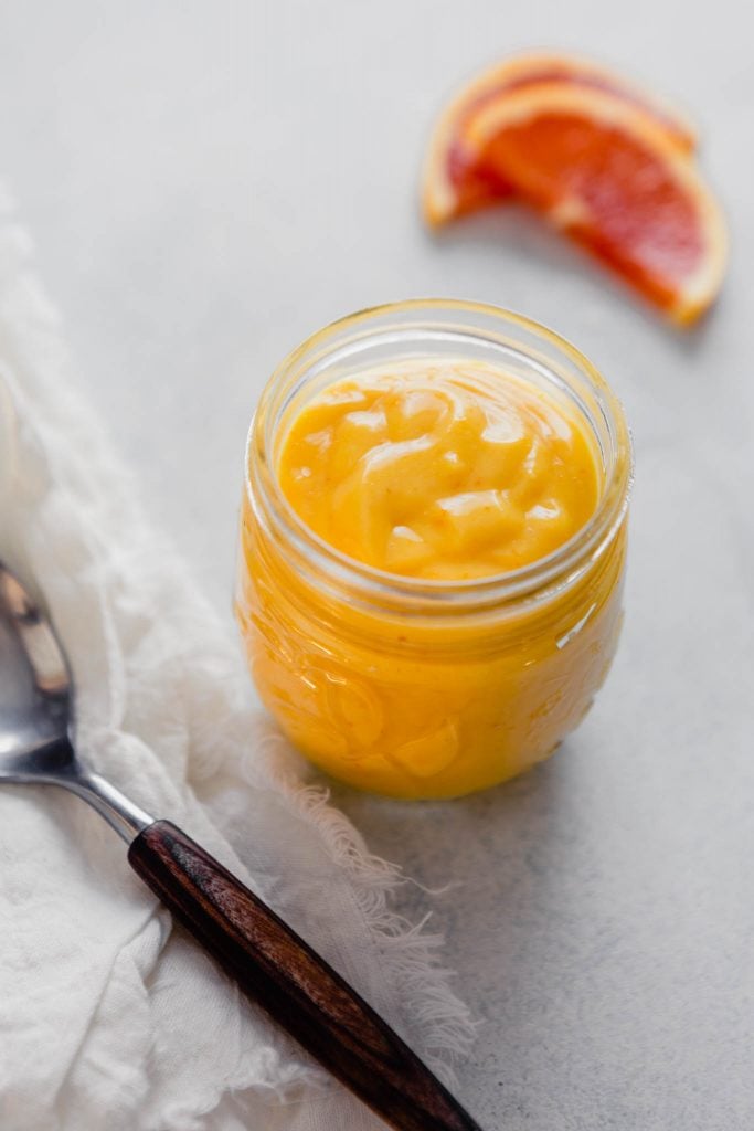 Side angle of orange curd in a small glass jar 