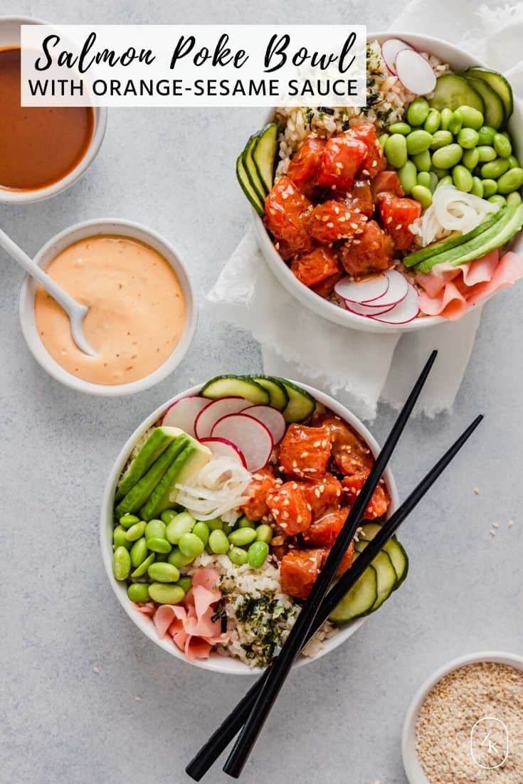 Overhead image of two bowsl filled with raw salmon, edamame, cucumbers, ginger and avocado set on a blue table with bowls of sauce and chopsticks