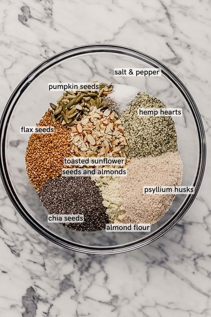 Overhead image of nuts and seeds in a glass bowl set on a marble table