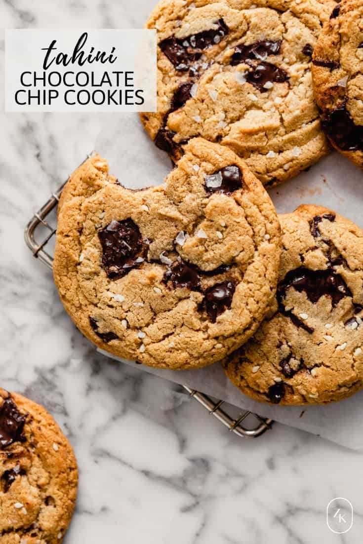 Overhead image of chocolate chip cookies stacked on a cooling rack on top of a marble table.