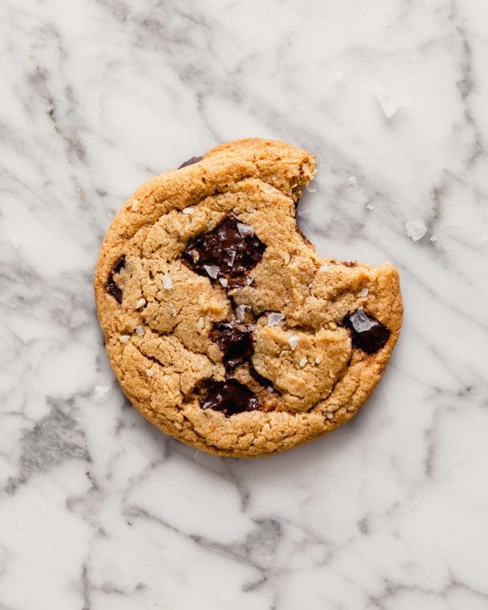 Overhead image of one cookie with a bite taken out of it set on a marble table