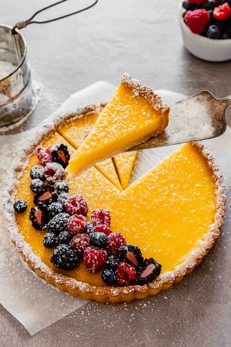 side angle of a piece of lemon tart being held up on a spatula