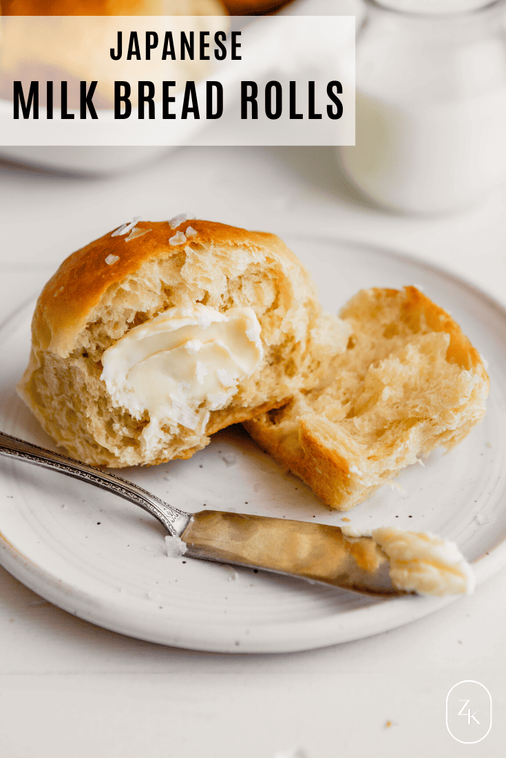 Side angle image of a milk roll topped with butter set on a plate