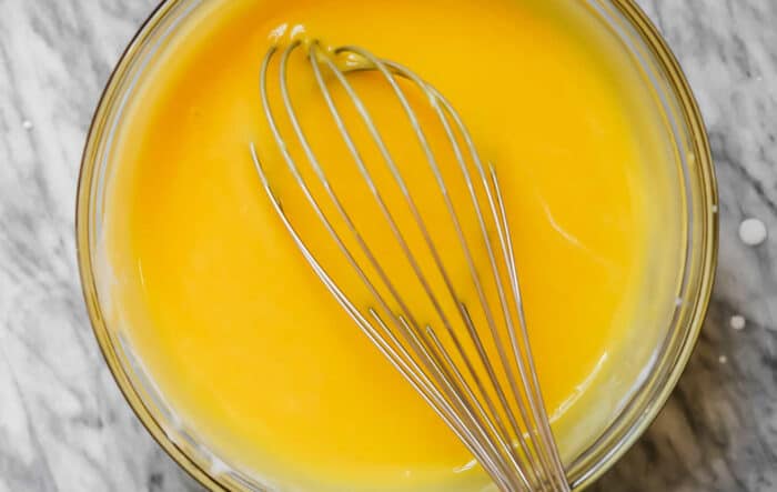 lemon curd in a glass bowl with a whisk