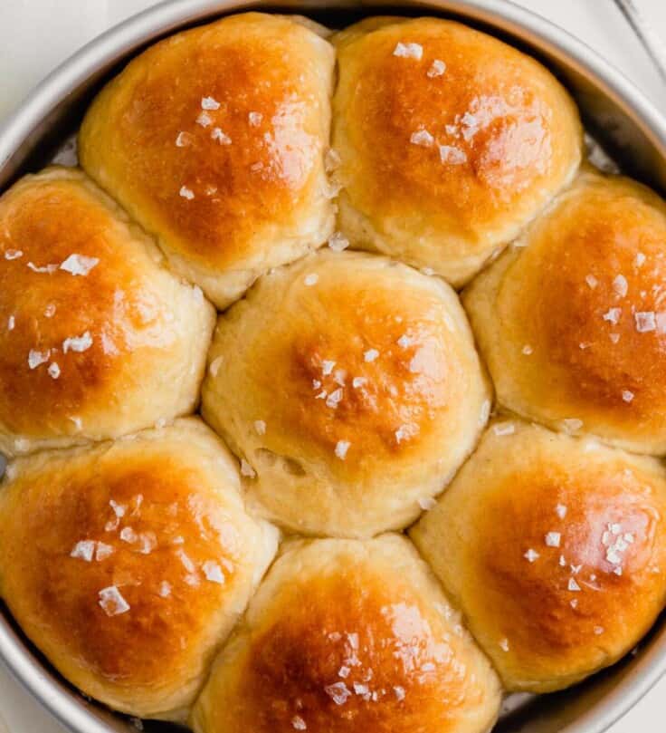 Overhead image of milk rolls in a round cake pan set on a white table