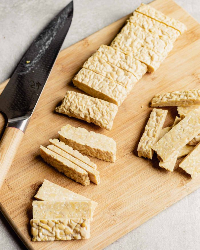 tempeh cakes being cut into smaller, thinner pieces