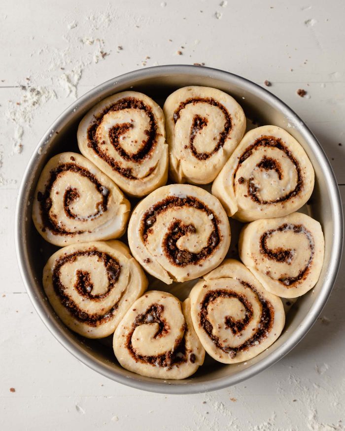 overhead image of unbaked, proofed cinnamon rolls in a round cake pan