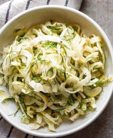 shaved fennel in a dish with lemon dest, fennel fronds and black pepper