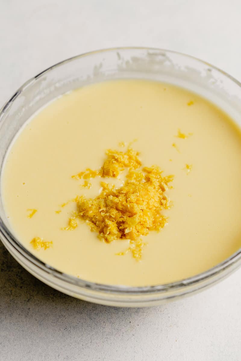 Yellow lemony egg and oil mixture in a mixing bowl.
