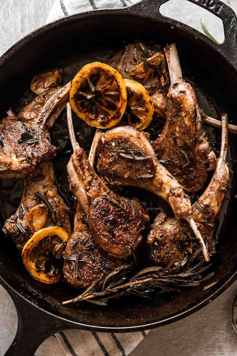 Overhead image of lamb chops in a cast-iron skillet set on top of a stripped towel.