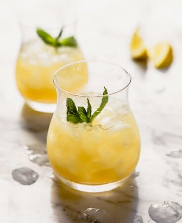 Yellow-colored cocktail in a whiskey glass with crushed ice and a mint sprig.