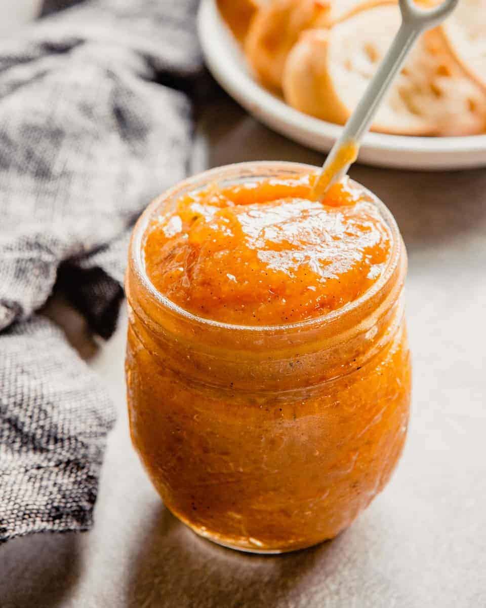 image of orange-colored jam in a glass Ball jar with a white spoon sticking out of it