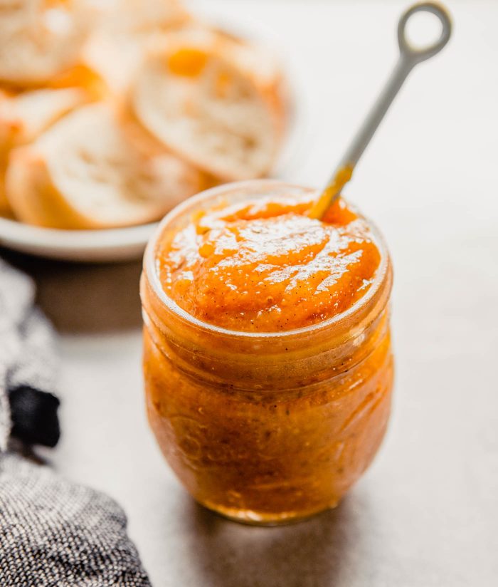 image of orange-colored jam in a glass Ball jar with a white spoon sticking out of it